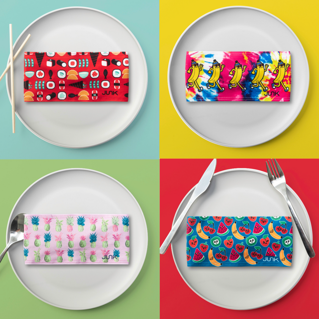 JUNK Food Headbands on plates. Sushi headband on the top left, then a banana headband with a multicolored background, bottom left is a pink headband with pink blue and green pineapples, then the bottom right is a fruit headband with a blue background.