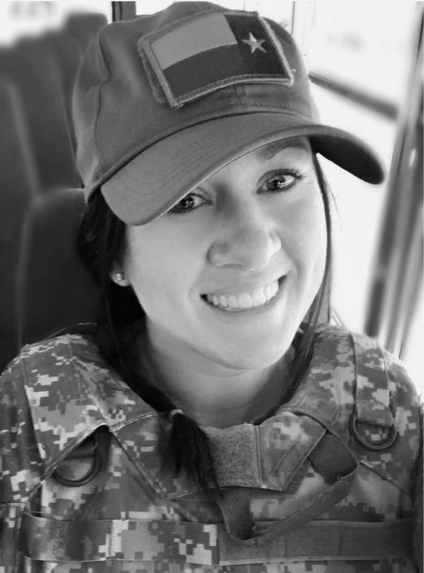 black and white photo of woman with dark hair and texas flag hat smiles at the camera