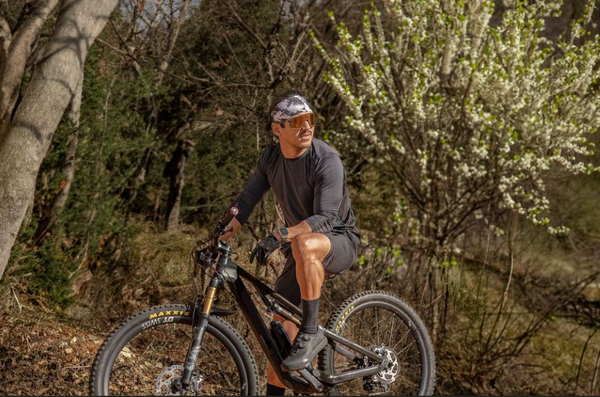 Man in sunglasses and junk headband on a bike in spring setting