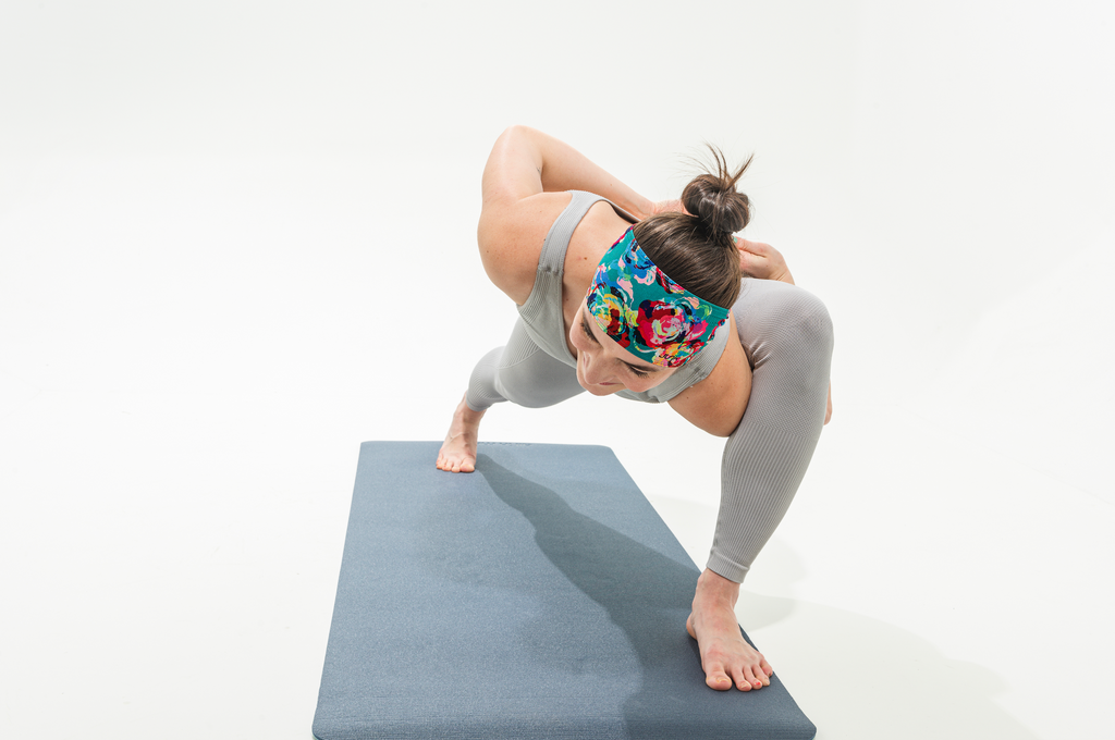 Claire in a yoga pose leaning forward showing off her floral JUNK headband