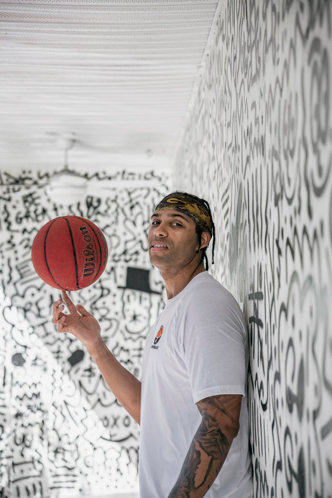 Man in a graffiti room wearing an HBCU Headband spinning a basketball.