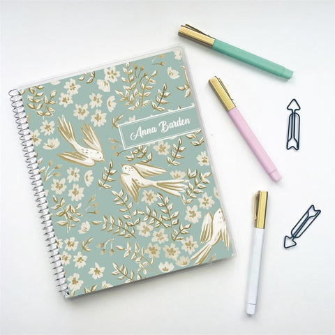 Pale aqua planner with pens on white desk