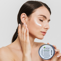 Woman using Perfectly Natural Skin's Aloe & Jojoba Cleansing Cream while holding jar in hand