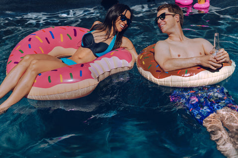 two people in a pool on donut floats 