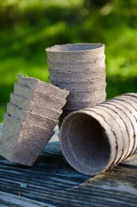 Cow pots and peat pots stacked on picnic table in garden.