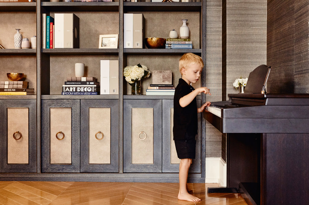 Kid playing the piano in front of a bookshelf with Savor products.