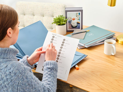 Woman at desk pealing a label to use on a something blue family emergency binder