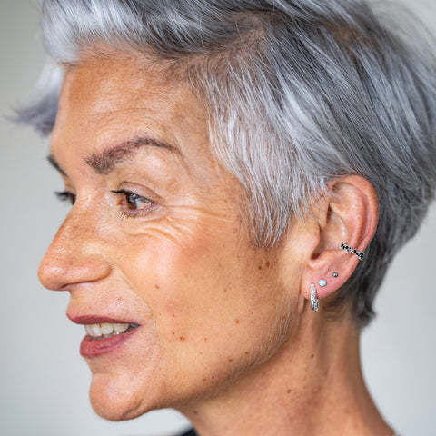 Model wears a series of lobe and helix ear piercings 
