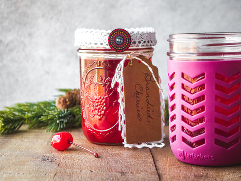 A mason jar filled with brandied cherries and festooned with a pretty red ribbon and homemade gift tag.