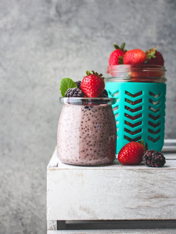 Two jars with chia pudding topped with berries.