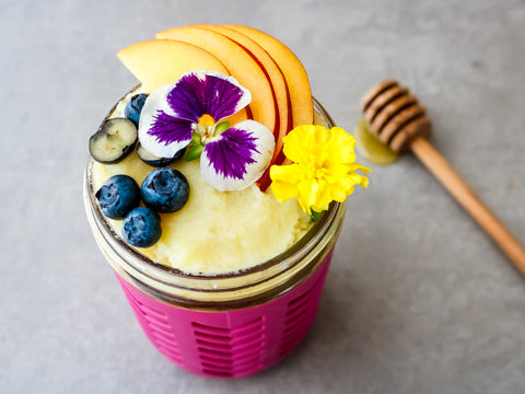Whipped sweet potato topped with sliced peaches and berries in a mason jar.