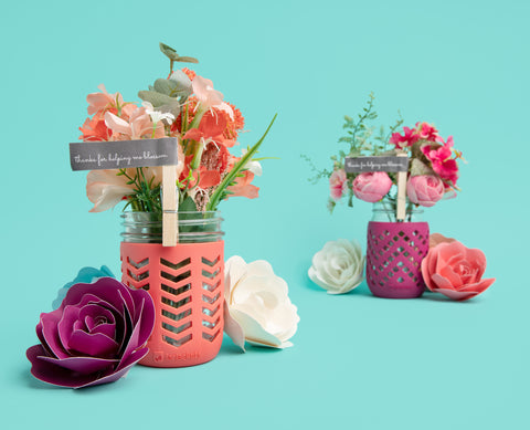 16oz mason jars adorned with JarJackets silicone mason jar sleeves and containing fresh spring flowers in pinks and coral colors.