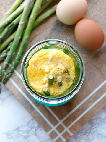 Two eggs next to a mason jar with a baked asparagus and sun-dried tomato frittata inside.
