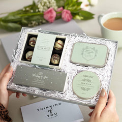 Open 'Thinking of you' gift set with greeting card. Includes candles, skin balm, chocolate truffles and tea