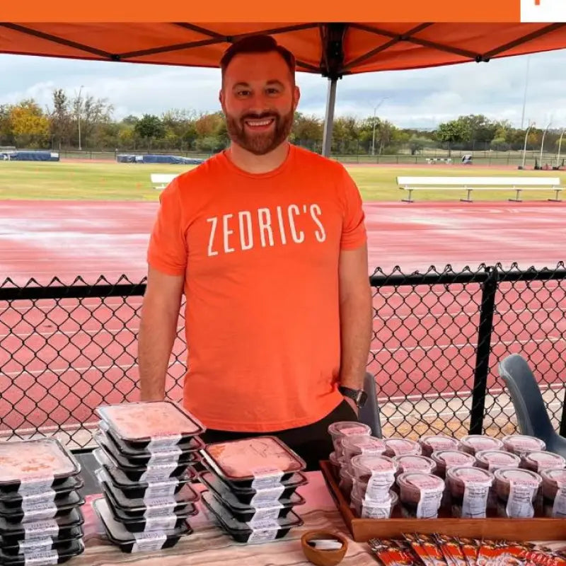 Man smiling at a fitness camp booth with pre-packed meals.