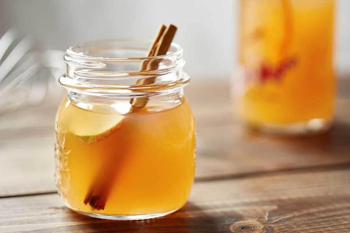 A small jar of rich apple cider vinegar on a wooden table with a wooden stirrer