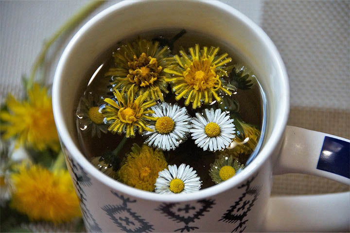 A mug of floral dandelion tea with the flowers brewing