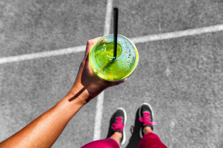 A person holding a cup of green juice during exercise