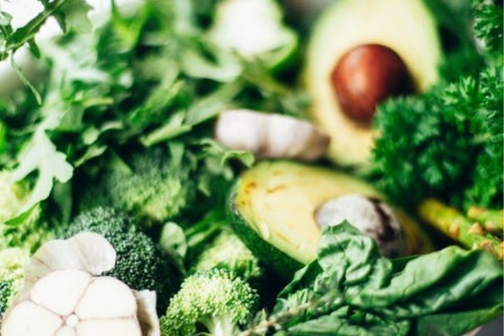 A photo of green leafy vegetables and avocados