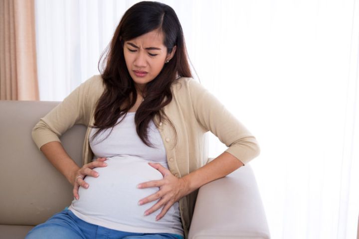 A pregnant woman holding her belly in pain