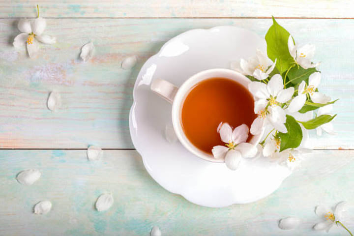 A white tea cup with flowers and leaves decorated around it