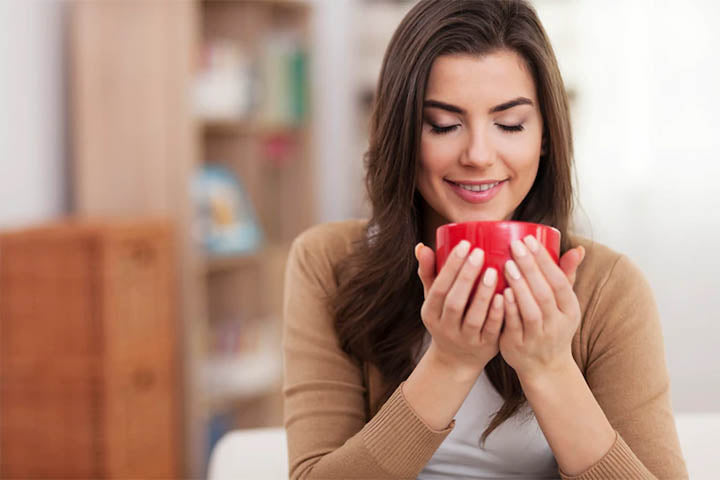 A woman enjoying the aroma of a cup of tea in her hand