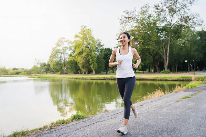 A woman running outdoors appreciating nature with a smile