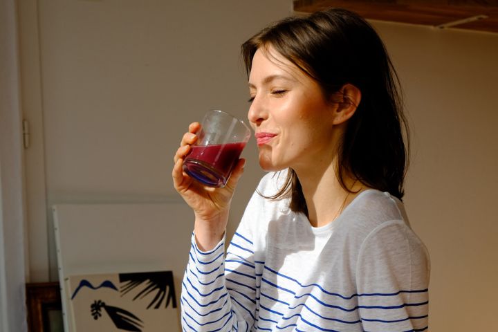 A woman sipping a glass of juice