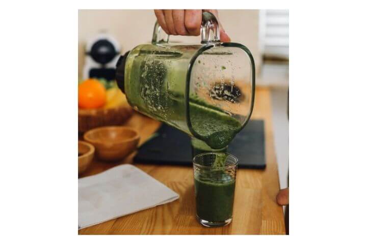 Liver green smoothie being poured from a mixer jar to a glass