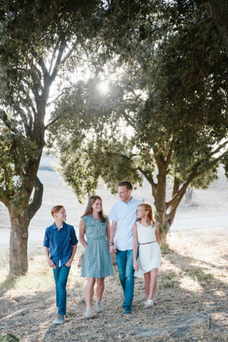 a family of four people walking through nature happily