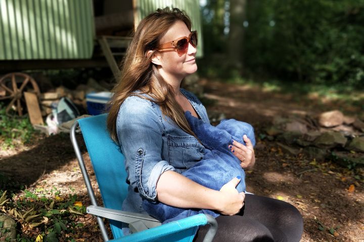 a pregnant woman in denim shirt breastfeeding her kid