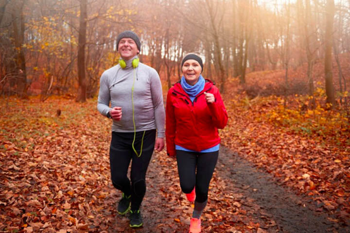 an elderly couple running in a forest area in warm clothing