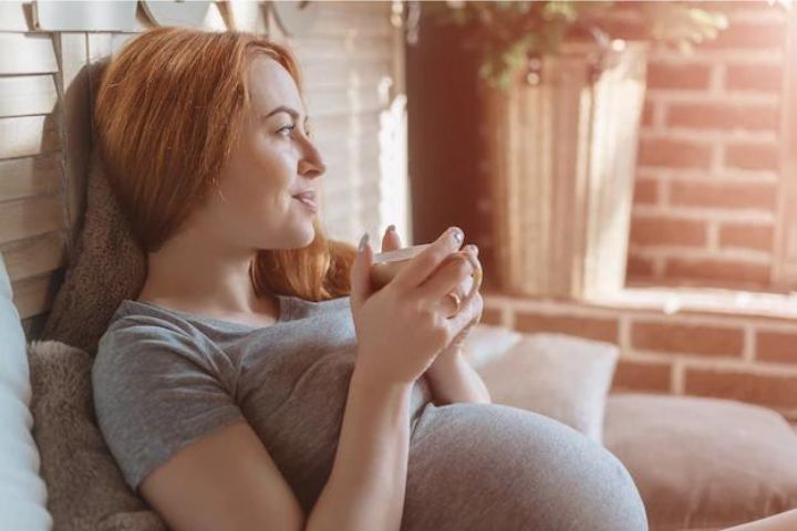 happy-pregnant-woman-with-cup-drinking-tea-home