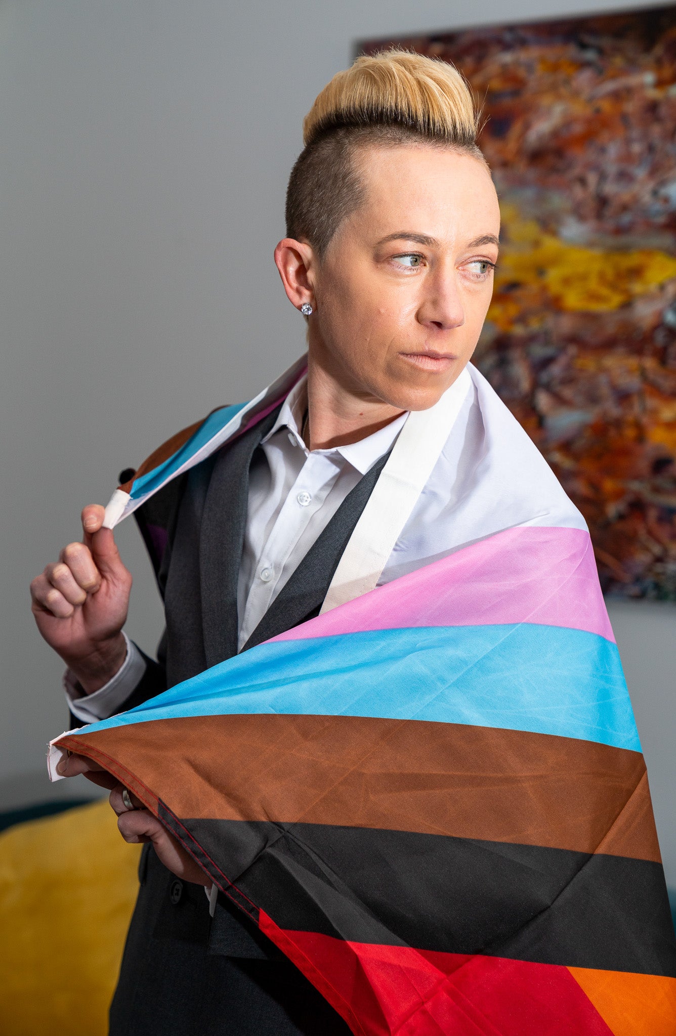 Jo Lohman Wearing Pride Flag Flag Around Their Body in a Charcoal Gray Kirrin Finch Suit