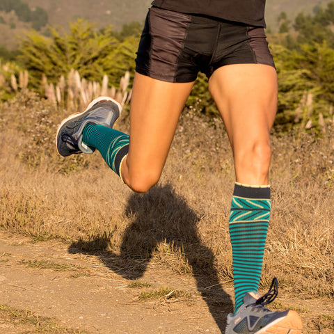 Legs of trail runner wearing slate compression socks with thin stripes and yellow accents