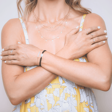 Ashley wearing layered necklace, rings, and stacked bracelets