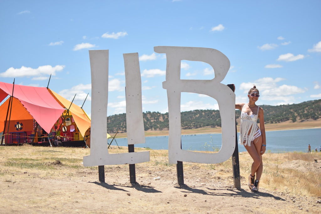 Girl wearing white beaded fringe collar at Lightning in a Bottle Music Festival in front of the LIB Sign 