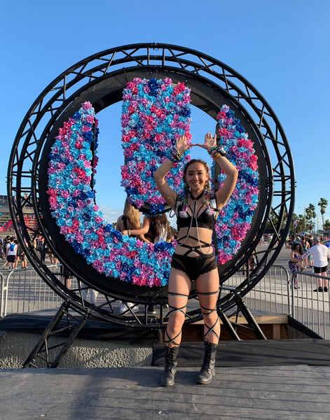 Raver Wearing Black Rave Outfit in Front of Bright Flowers at Ultra Music Festival
