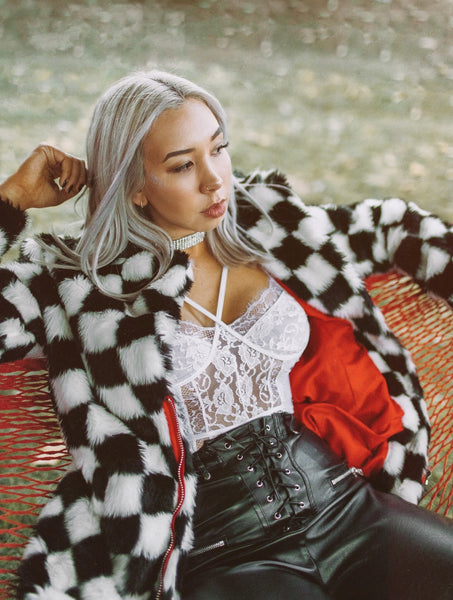 Wenzday wearing a checkered faux fur coat and black pleather pant