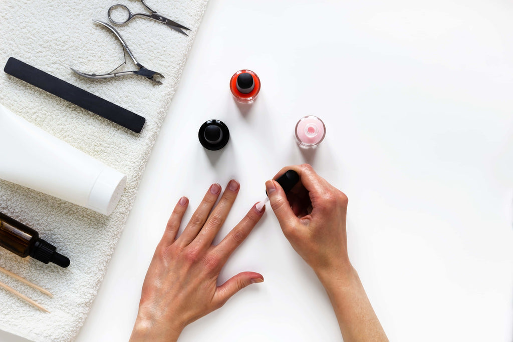 A woman applying a coat of nail polish on her nails