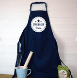 A personalised star baker apron hanging on the wall next to a bag of flower and a jug of baking utensils 