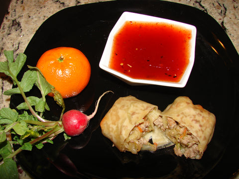 up close photo of red pepper jelly dipping sauce on plate with eggroll