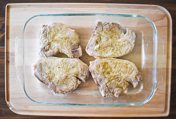 seared pork chops in baking dish with extra chugwater chili green chili seasoning on them