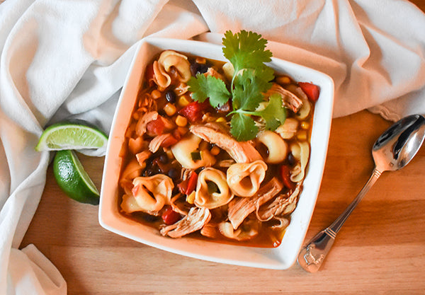 southwest chicken tortellini soup in bowl garnished with limes and cilantro