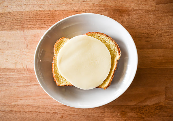 slice of provolone cheese added to bread 