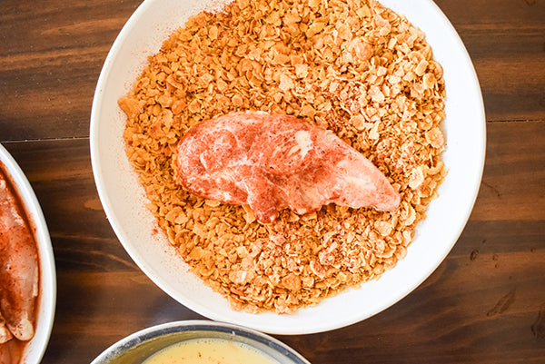 egg and milk coated chicken tenders added to seasoned cornflakes to be coated