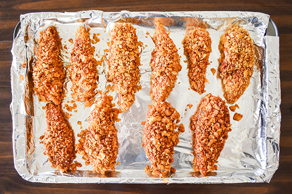 cornflake coated chicken tenders on baking sheet ready to be baked