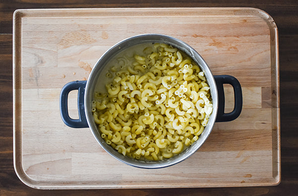 macaroni noodles added into pot with cheese sauce