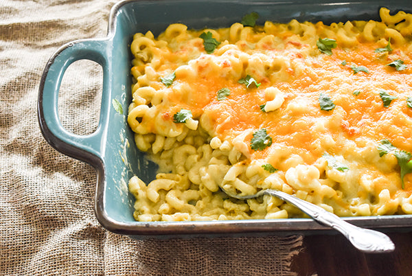Green chile mac and cheese in a baking dish with a spoon 