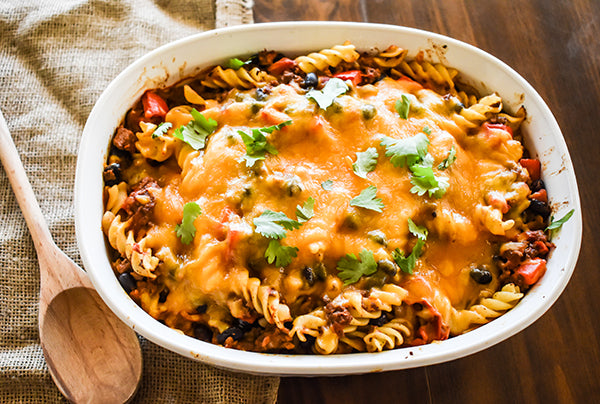 bison taco pasta bake in baking dish with cheese on top and garnished with cilantro